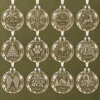 Twelve personalised glass Christmas baubles with twelve different engraving designs