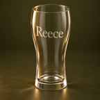 Close view of Reece engraved on a 570 ml beer glass against a dark olive backdrop